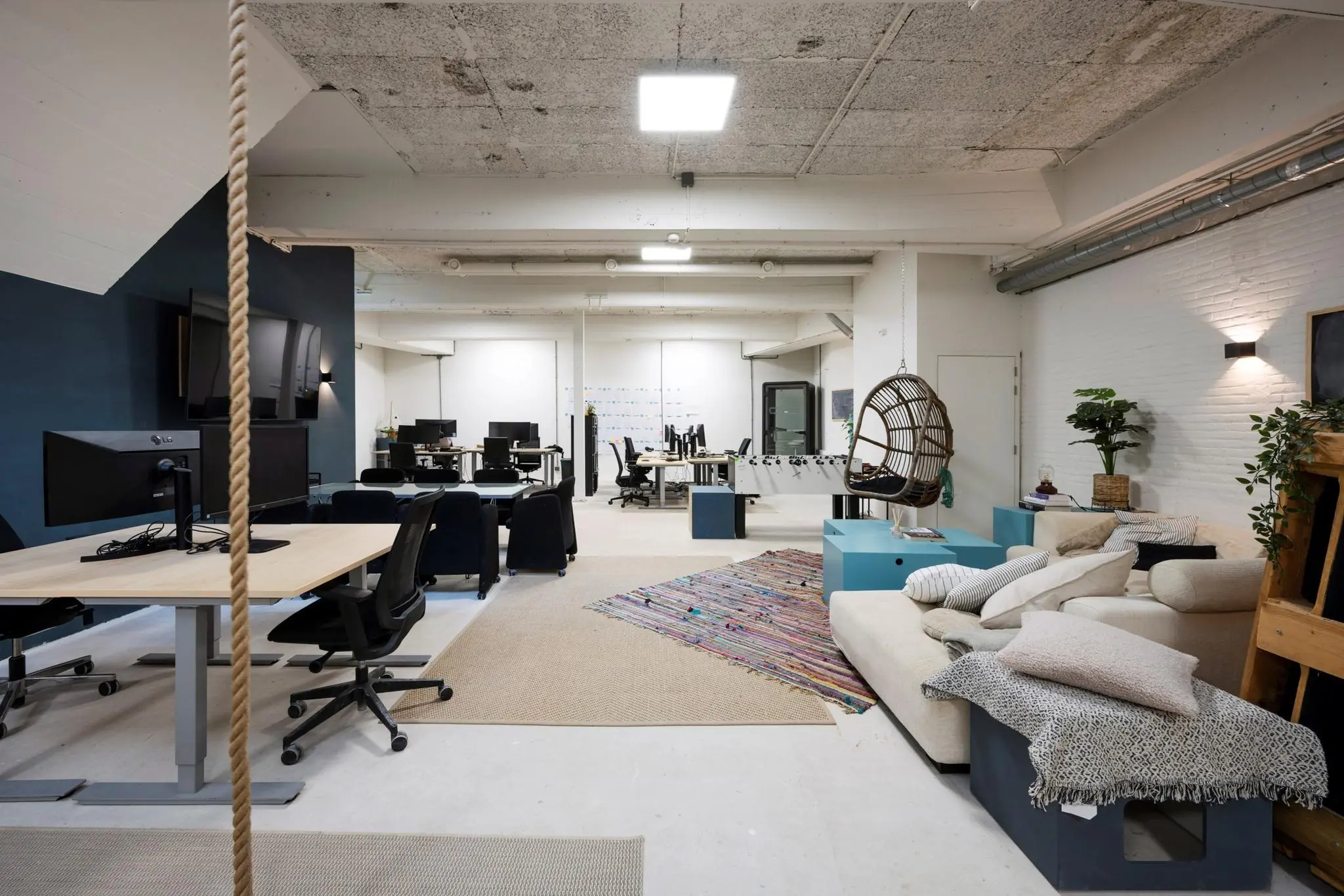 Modern en creatief ingericht kantoor aan de James Wattstraat met bureaus, loungehoek, hangstoel en tafelvoetbaltafel.